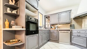 Een keuken met grijze kastjes, een zwarte oven en een witte vaatwasser.