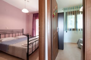 A bedroom with a bed, a wardrobe, and a bathroom visible through an open door. - Konstantina`s House by Rentals Pro - Afytos Halkidiki (Afytos)