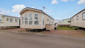 En rad med husvagnar, en asfalterad uppfart, ett trästaket och en klar himmel.