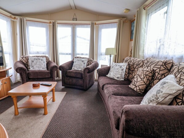 Ein gemütliches Wohnzimmer mit zwei Sesseln, einer Couch und einem Couchtisch aus Holz.