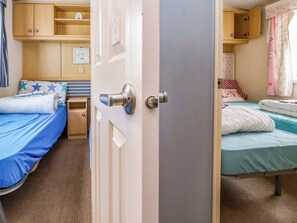 Ein Schlafzimmer mit zwei Betten, einem Kleiderschrank und einem kleinen Regal mit einer Uhr.