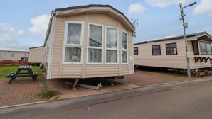 Ett litet, enplanshus på hjul med en böjd framsida, stora fönster och en liten veranda.