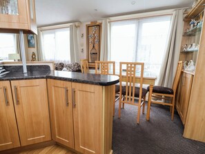 Eine Küche mit Holzschränken, einer Granit Arbeitsplatte und einem Essbereich mit Holztischen und einem Tisch.