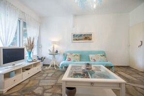 A living room with a television, a sofa, a coffee table, and a painting on the wall.