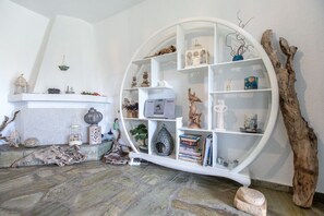 Une pièce avec une étagère circulaire blanche adossée à un mur blanc, contenant divers objets décoratifs et des livres.