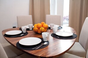 Een eettafel gedekt met borden, bekers en een schaal oranje.