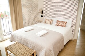A hotel room with a bed, a bench, a wall with a geometric pattern, and a window with curtains. - Homey-Seville Amazing Apartment Calle Arfe 1 (Sevilla)