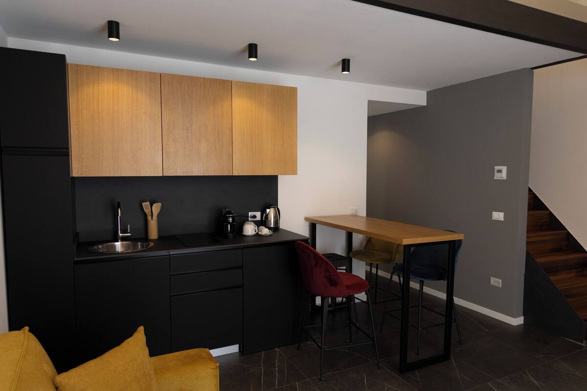 A modern kitchen with black cabinets, a wooden countertop, and a bar stool.