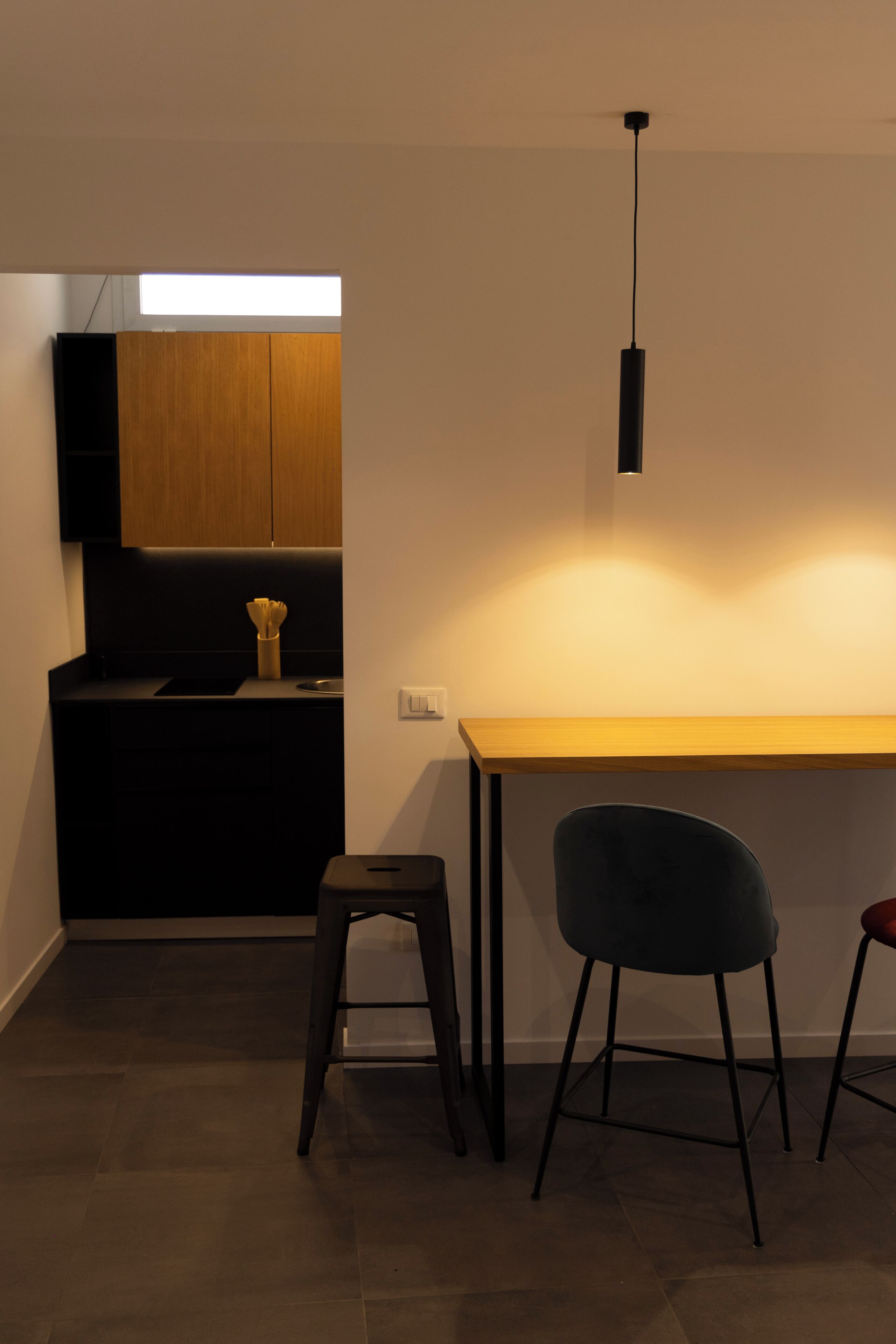 Eine moderne Küche mit einer Holzausziehtafel, einem schwarzen Hocker und einem einzelnen Stuhl.