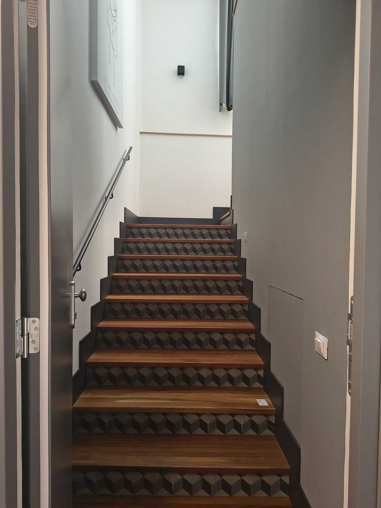 Un escalier avec des marches en bois et des motifs géométriques sur les murs.