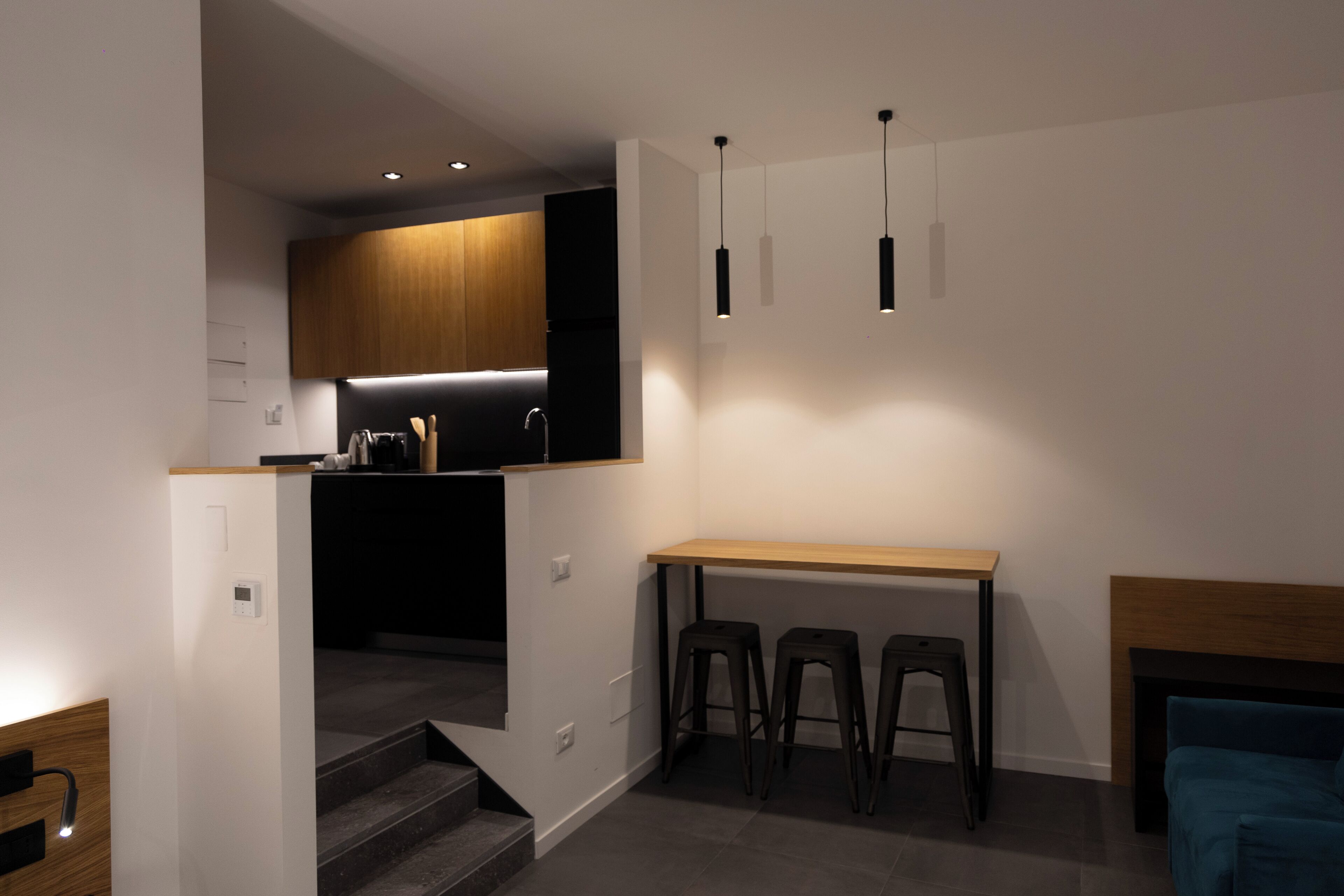 Una cocina moderna con encimera de madera, dos taburetes altos y luces colgantes.