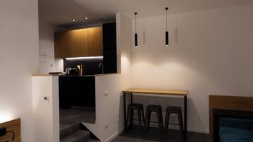 Una cocina moderna con encimera de madera, dos taburetes altos y luces colgantes.