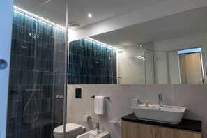 A modern bathroom with a glass shower enclosure, a white sink, and a mirror above the sink.