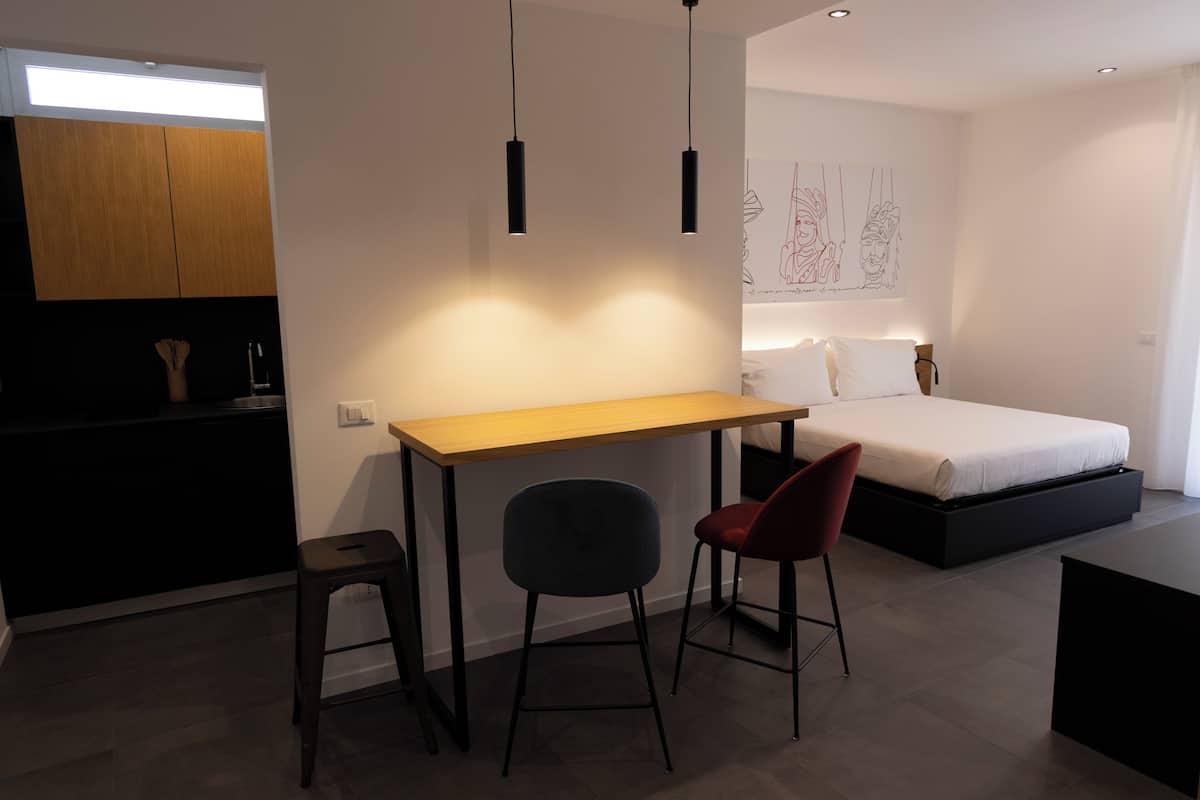 A modern bedroom with a bed, bedside table, and a desk with two chairs.