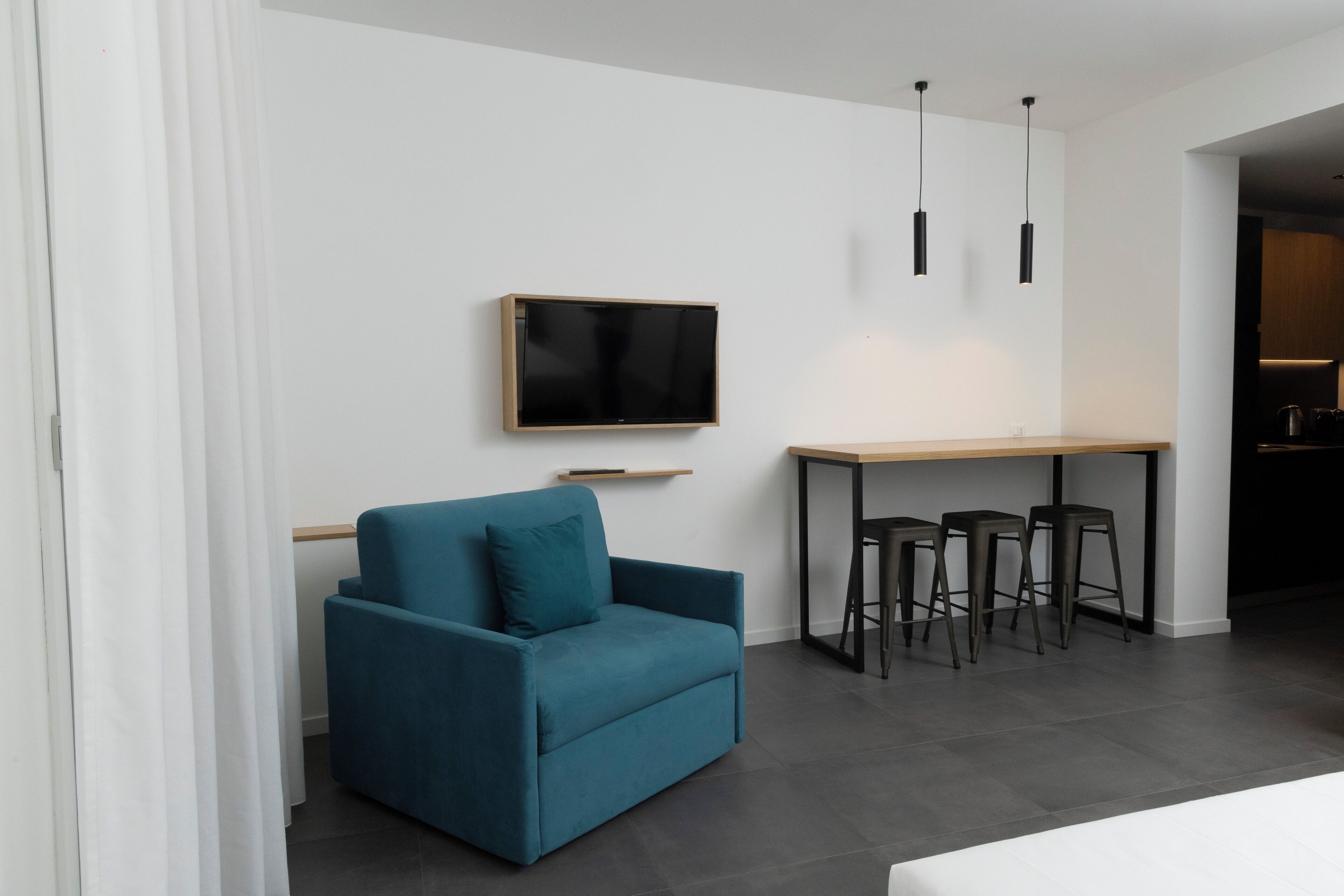 A modern living room with a sofa, a TV, and a bar area with stools.
