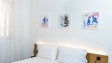 Ein modernes Schlafzimmer mit einem Bett, weißen Vorhängen und drei an der Wand befestigten Kunstwerken.