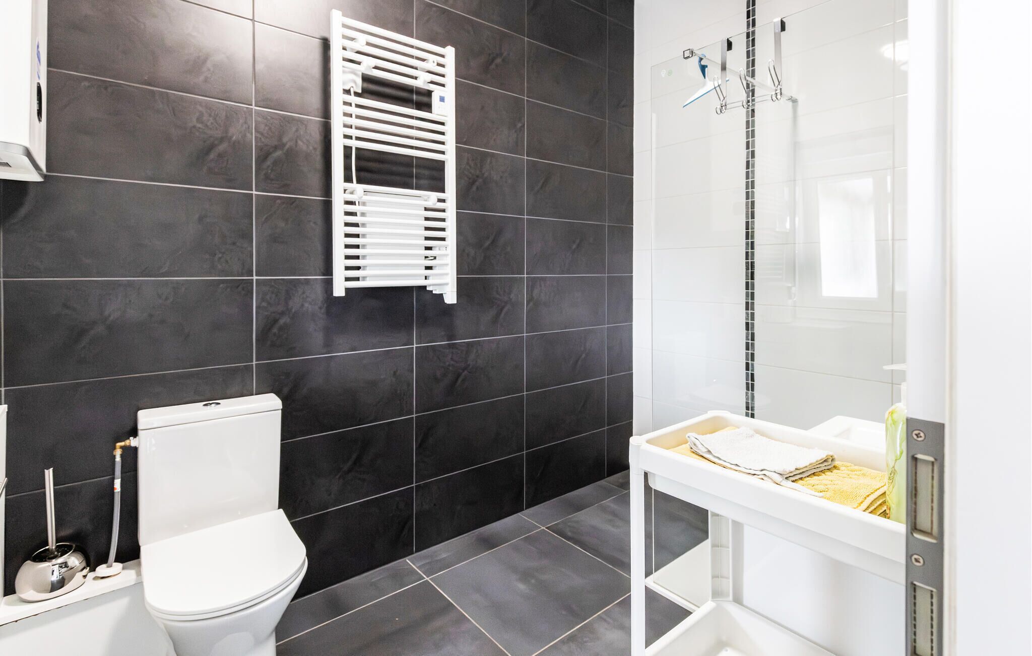 A modern bathroom with a toilet, a towel rack, and a shower area.