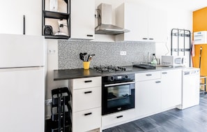 Eine kompakte Küche mit schwarz-weißer Spritzschutzleiste, einem Herd, einem Backofen und einer Mikrowelle.