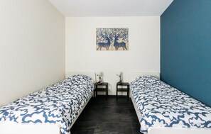 Ein kleines Zimmer mit zwei Einzelbetten, einem Nachttisch mit Lampe und einem Wandbild.