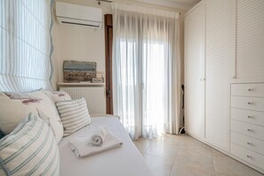 A bedroom with a bed, a radiator, a window with curtains, and a wardrobe. - Fibes Luxury Living 2 by Rentals Pro - Mouries Halkidiki (Mouries)