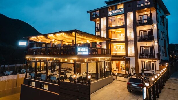 Um hotel com vários andares, com um restaurante com varanda chamado 'BROOKSIDE' e um bar chamado 'WALNUT' no último andar.