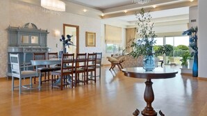 A spacious room with a dining area, a large window, and a chandelier. - Villa Anastasia - Private Heated Pol (Chania)
