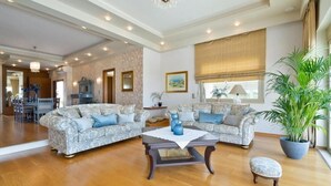 A spacious living room with two patterned sofas, a coffee table, and a large potted plant. - Villa Anastasia - Private Heated Pol (Chania)