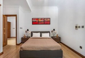 A bedroom with a bed, nightstands, a painting, and a door leading to another room. - L12 Adjacent to Aphrodite Hills- Pool & Terrace (Kouklia)