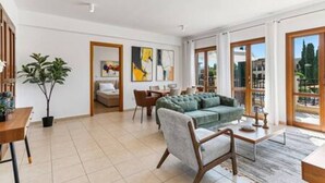 A spacious living area with a sofa, chairs, a coffee table, and a dining table. There is a potted plant and artwork on the walls. - BF12 Adjacent to Aphrodite Hills - Pool & Terrace (Kouklia)