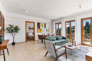 A spacious living area with a sofa, chairs, a coffee table, and a dining table. There is a potted plant and artwork on the walls. - BF12 Adjacent to Aphrodite Hills - Pool & Terrace (Kouklia)