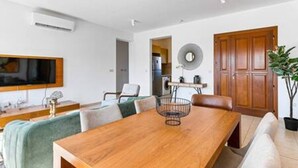 A modern dining area with a wooden table, chairs, a television, and a potted plant. - BF12 Adjacent to Aphrodite Hills - Pool & Terrace (Kouklia)