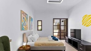Een moderne slaapkamer met een bed, een televisie en kunstwerken aan de wand.