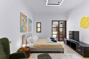 A modern bedroom with a bed, a TV, and artwork on the walls. - L02 Adjacent to Aphrodite Hills - Pool & Patio (Kouklia)