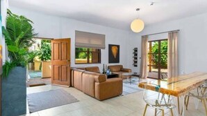 Een moderne woonkamer met een bank, een eettafel en een groot raam.