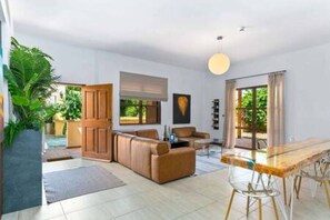 A modern living room with a sofa, a dining table, and a large window. - L02 Adjacent to Aphrodite Hills - Pool & Patio (Kouklia)