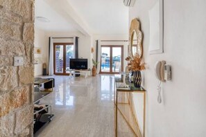 A spacious living area with a stone wall, a television, and a large mirror. - HG07 Adjacent to Aphrodite Hill - Pool & Terrace (Kouklia)