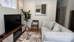 Una sala de estar con televisor, sofá y planta.