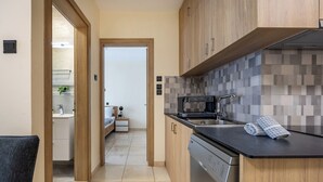 A modern kitchen with wooden cabinets, a dishwasher, and a tiled backsplash. - 75 Prokymea - Steps from the Sea, Balcony (Limassol)