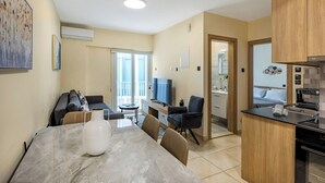 A modern kitchen with a dining area, a TV, and a view to the outside. - 75 Prokymea - Steps from the Sea, Balcony (Limassol)