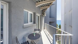 A balcony with a table and chairs, air conditioning units, and a view of the sea. - 75 Prokymea - Steps from the Sea, Balcony (Limassol)