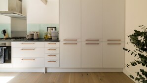 A modern kitchen with white cabinets, wooden handles, and a stainless steel range hood. - Sage Tones with Private Patio (London)