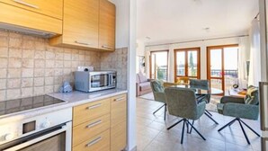 Una cocina moderna con armarios de madera, un microondas y un comedor con mesa y sillas.