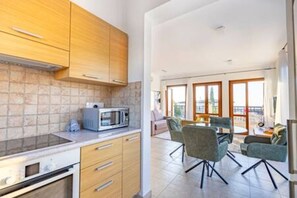 Een moderne keuken met houten kastjes, een magnetron en een eethoek met een tafel en stoelen.