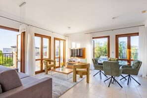 Een moderne woonkamer met een bank, eettafel, stoelen en een televisie.
