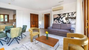 Una sala de estar moderna con un sofá, sillas, una mesa de centro y un cuadro en la pared.