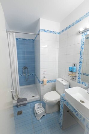 Ein Badezimmer mit Dusche, Toilette und Waschbecken, mit blauen und weißen Fliesen.