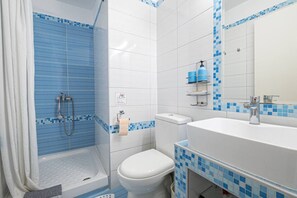 Une salle de bain équipée d’une douche, de toilettes, d’un lavabo et d’un miroir.