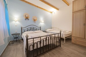 Une chambre à coucher avec un lit en métal, deux tables de chevet, une armoire et des lampes fixées au mur.