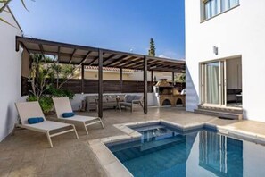 Ein Poolbereich mit LiegestĂŒhlen, einer Pergola und einem kleinen Pool.
