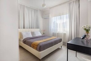 A modern bedroom with a bed, a bedside table, and a window with curtains.